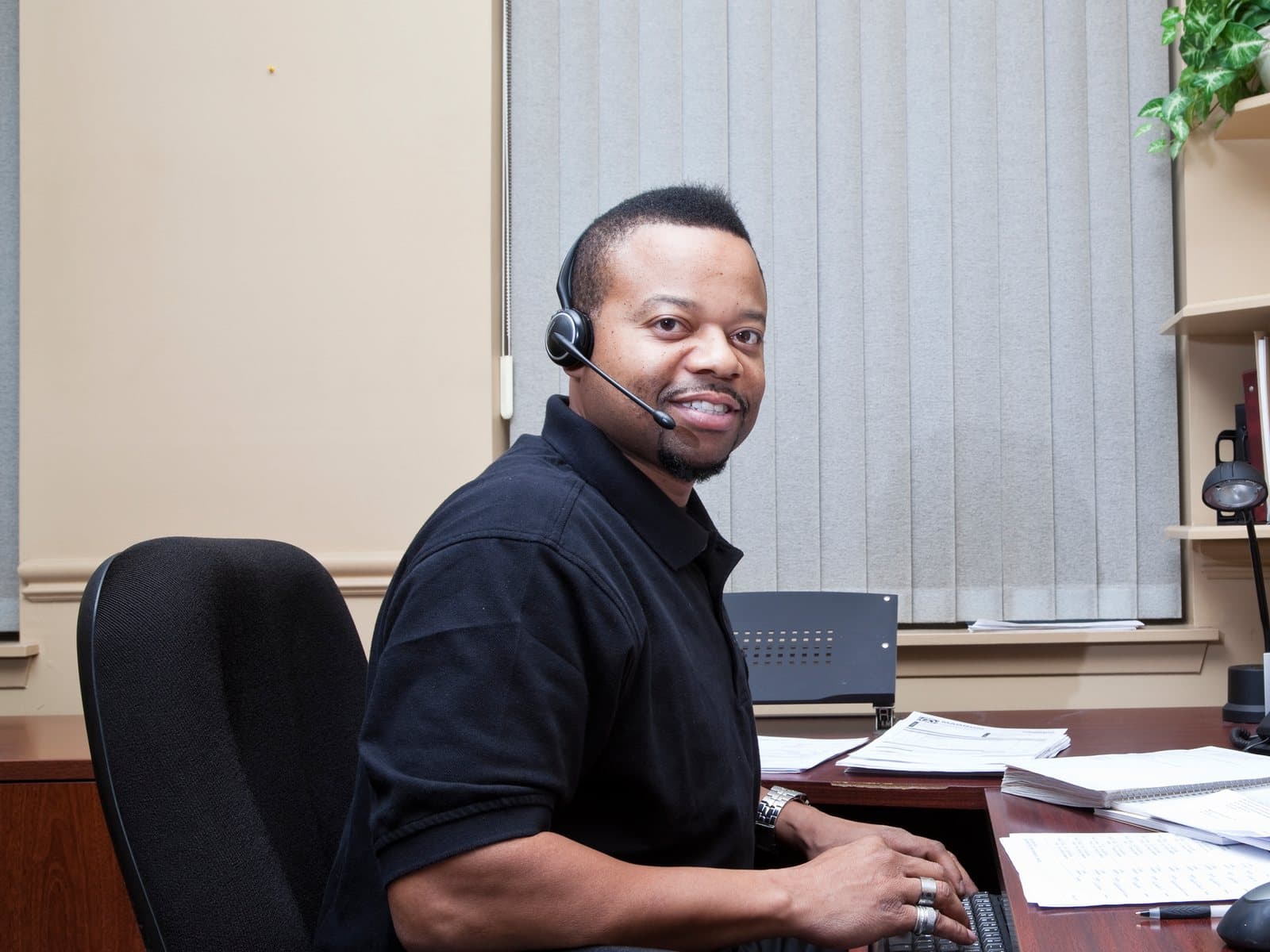 Andy at his desk in the HTS office, wearing a phone headset